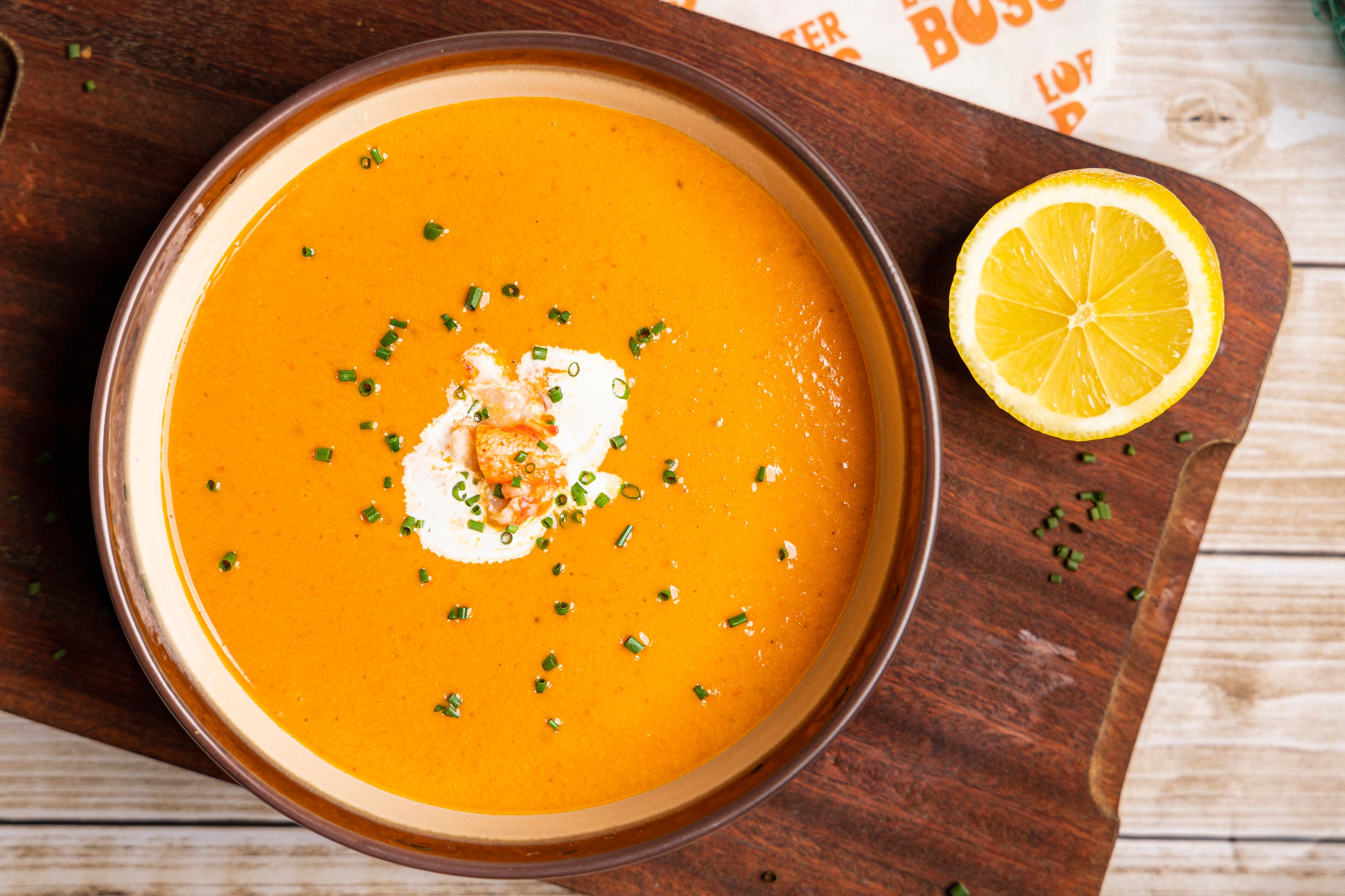 Lobster Bisque, Soup with lobster, by Lobster Boss Hong Kong on a wooden board on a Lobster Boss Hong Kong packing paper